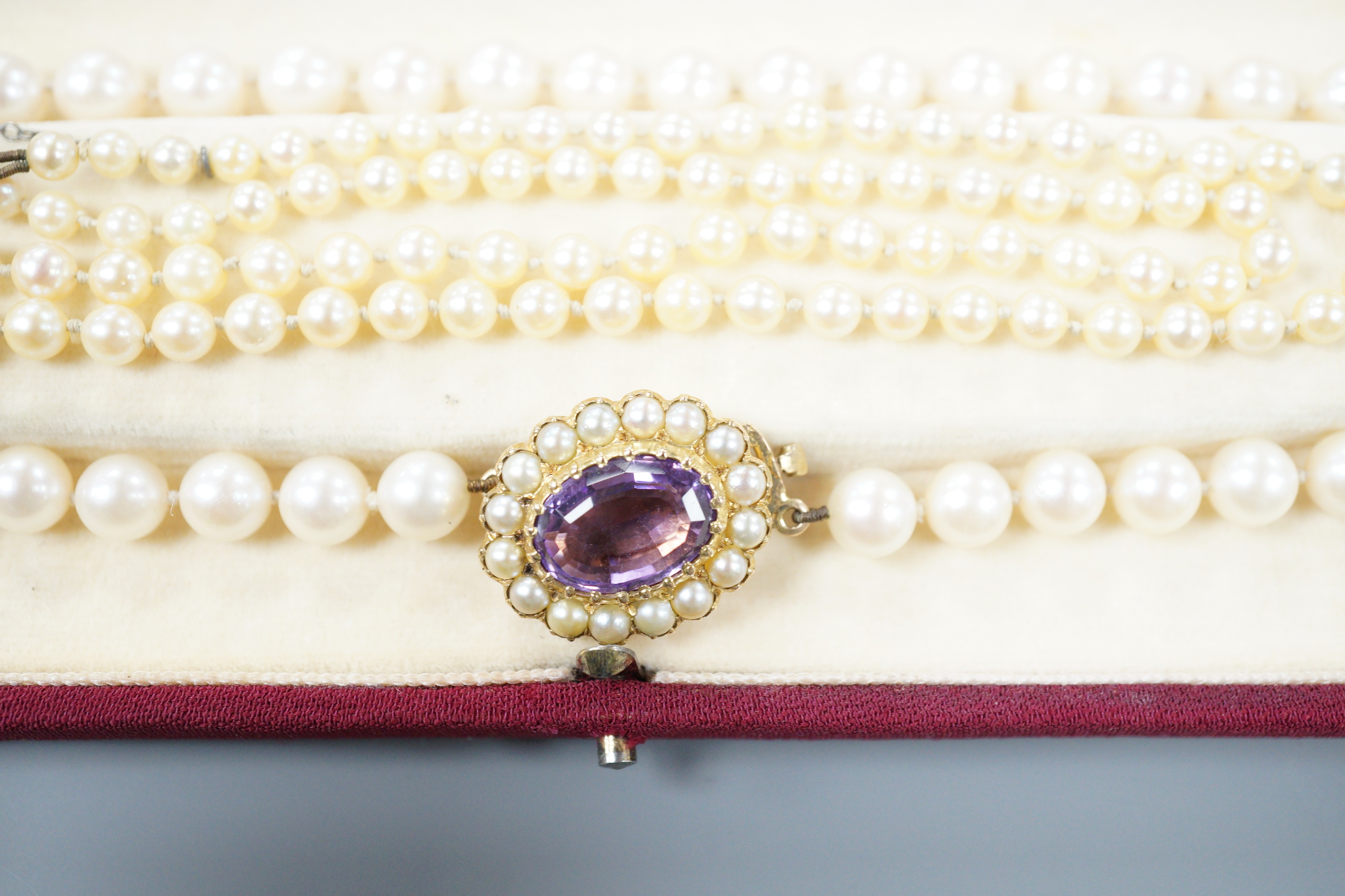 A modern single strand cultured pearl necklace, with 9ct, amethyst and cultured pearl set ova clasp, 44cm and one other single strand graduated cultured pearl necklace, with diamond chi set 9ct white gold clasp, 50cm.